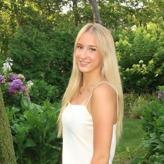 Anna, the AMW Tutoring founder, smiling in a garden among blue hydrangeas